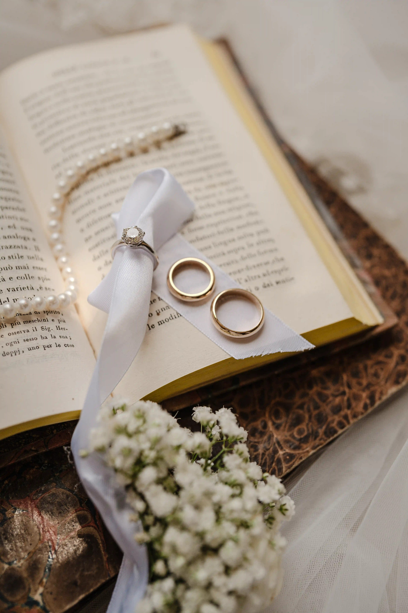 Wedding rings and engagement ring displayed on an antique book during bridal preparations at Castello Xirumi in Sicily