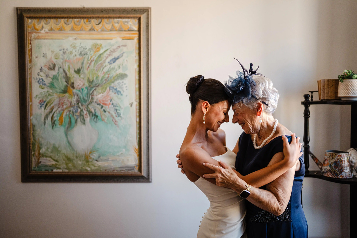 Bride sharing a tender embrace with an elderly family member during emotional pre-ceremony moments.